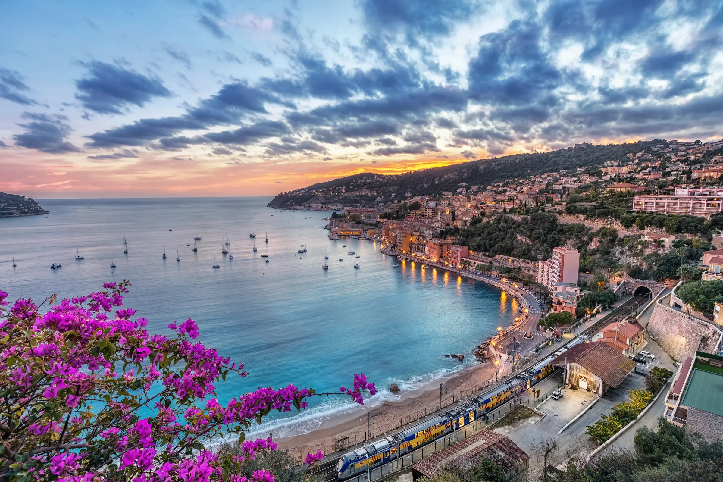 Sunset over the ocean with boats and beach at Villefranche-sur-Mer in the South of France — luxury France and Monaco travel with Eventra Bespoke